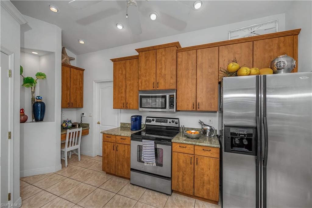 Kitchen with stainless steel appliances, wood finish cabinets, a ceiling fan, light tile patterned floors, and recessed lighting