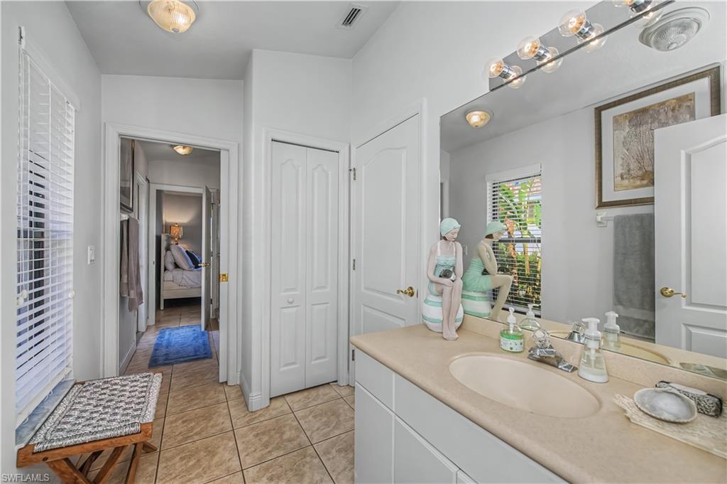Ensuite bathroom with a closet, vanity, and light tile patterned floors