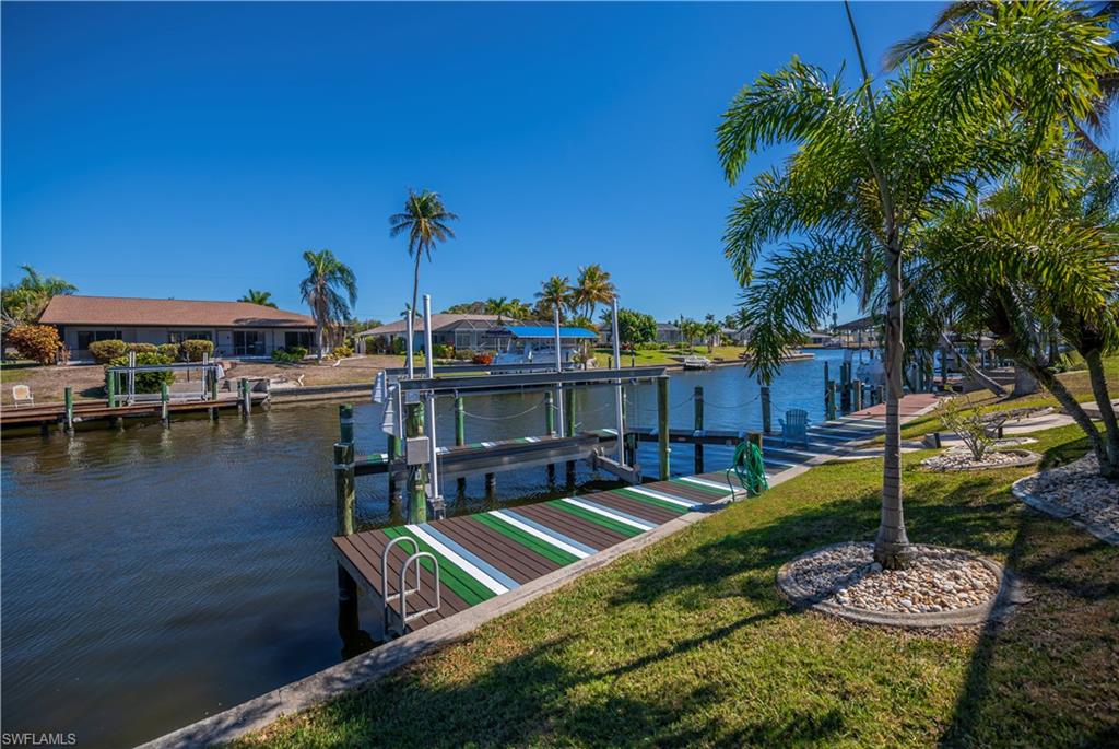 Dock with boat lift, a water view, and a residential view