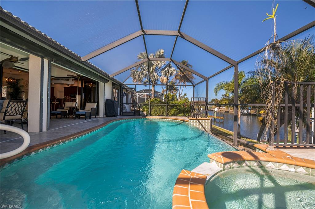 Relaxing pool / spa with a sunroom, a patio area, a lanai, a grill, and a water view
