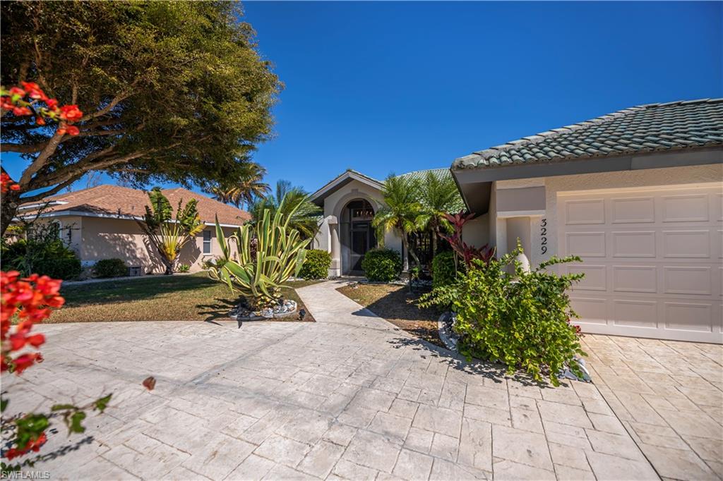 View of front of property with a tile roof, stucco siding, driveway, and a front lawn