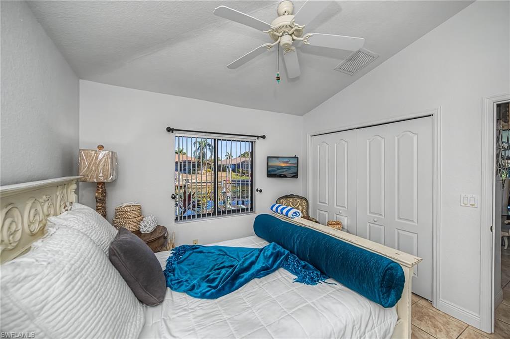 Tiled bedroom featuring lofted ceiling, a closet, and ceiling fan