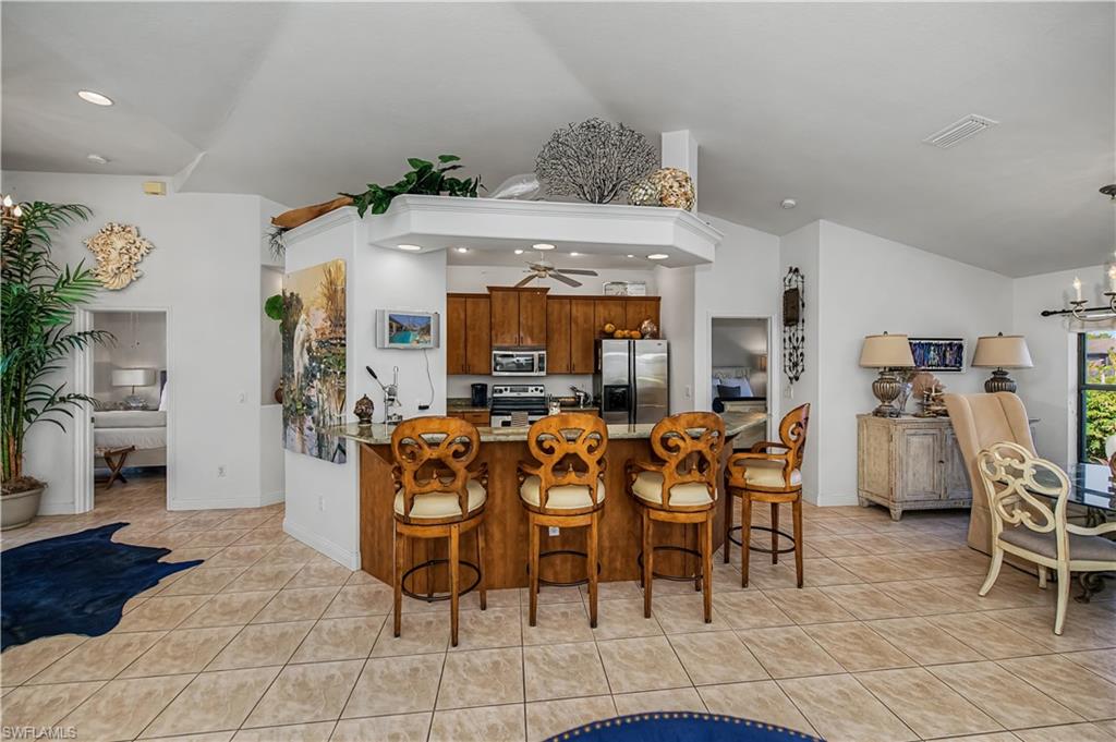 Kitchen featuring a chandelier, a peninsula, a breakfast bar, wood finish cabinets, and stainless steel appliances