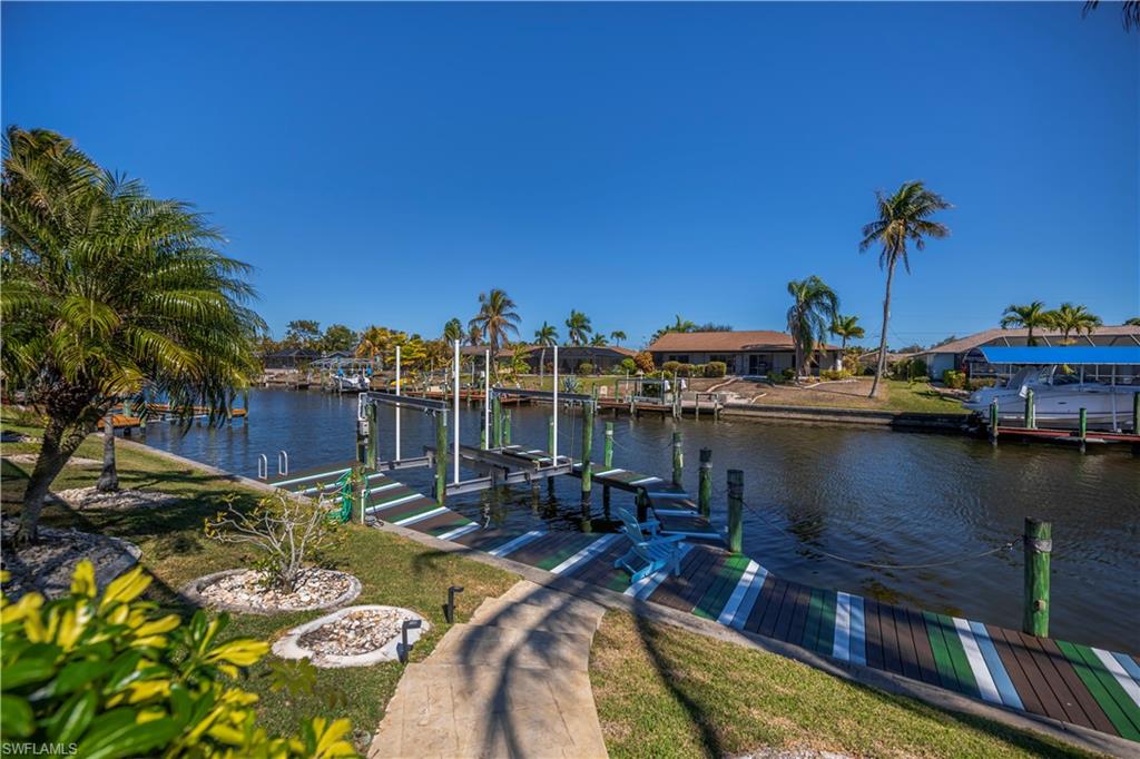 Dock area with boat lift, a water view, and a residential view