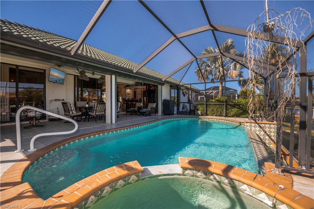Relaxing pool / spa with a patio area, a sunroom, glass enclosure, and grilling area