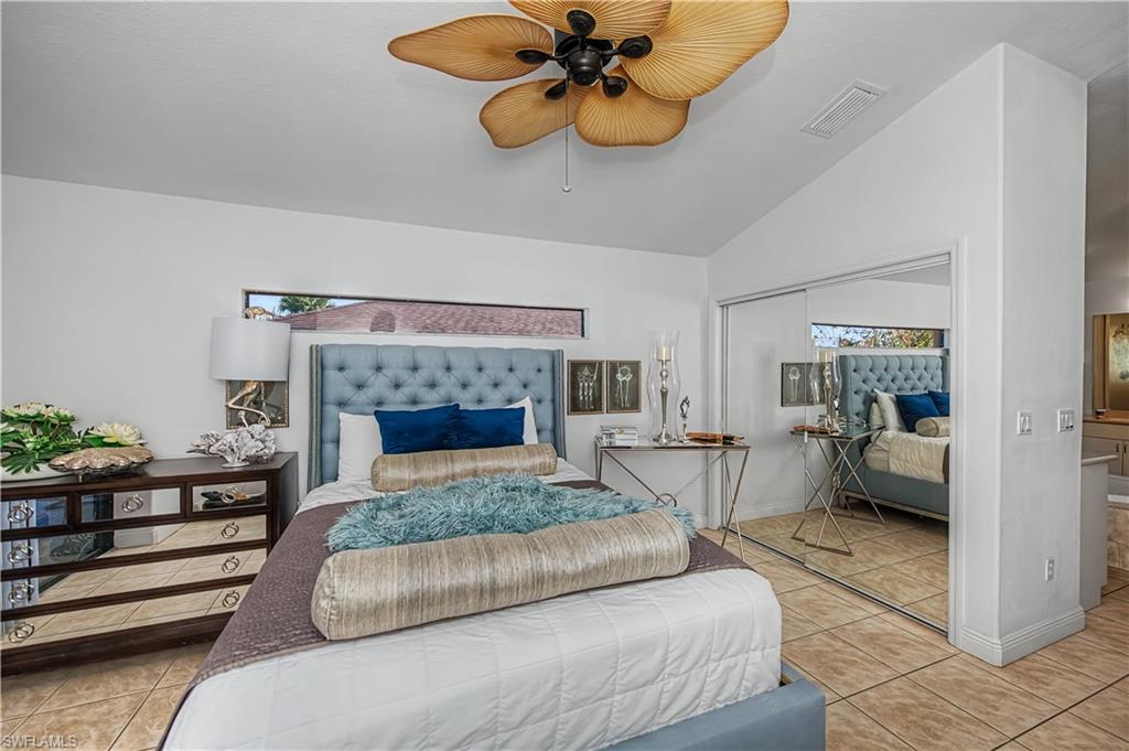 Bedroom with lofted ceiling, light tile patterned floors, a ceiling fan, and a closet