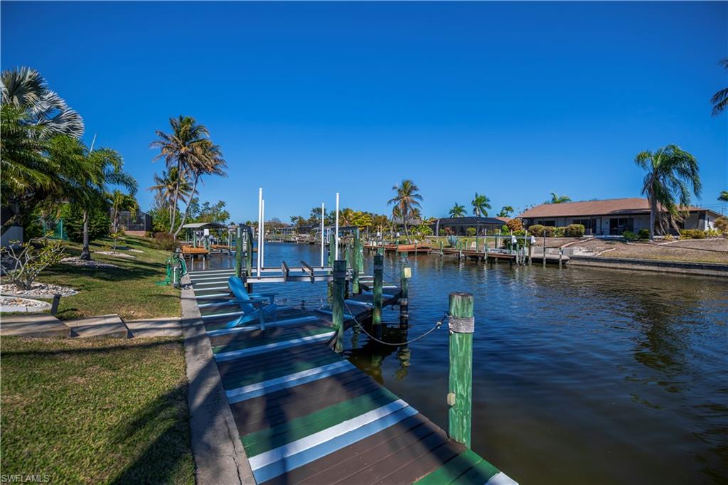 Dock area featuring a water view, boat lift, and a yard