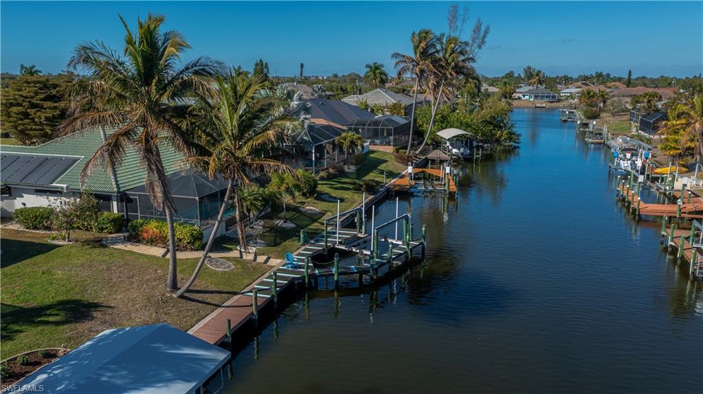 Dock area featuring a water view, boat lift, a lawn, a lanai, and a sunroom