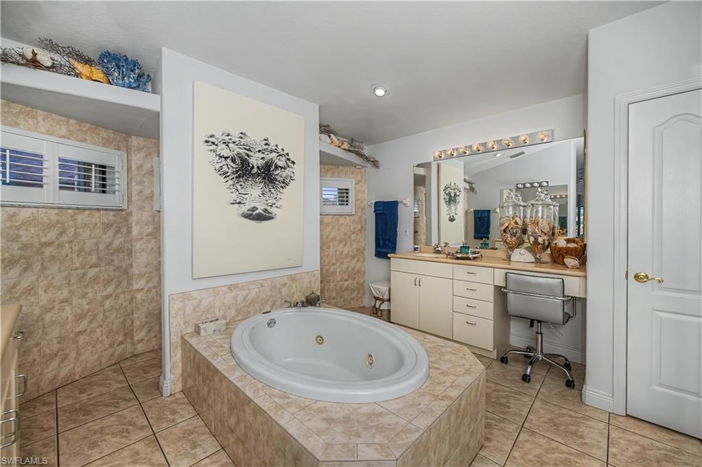 Full bathroom with vanity, a whirlpool tub, and light tile patterned flooring
