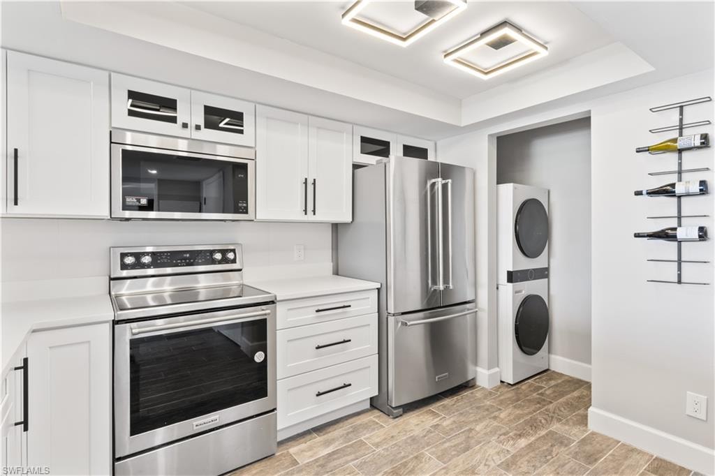 Bright kitchen with brand new white cabinets and a convenient laundry area featuring a new stackable washer and dryer.