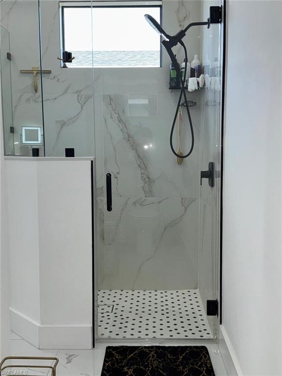 Bathroom with marble finish floor and a marble finish shower