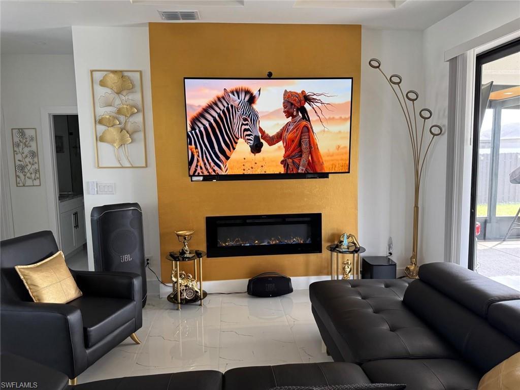 Living area featuring visible vents, marble finish floor, and a glass covered fireplace