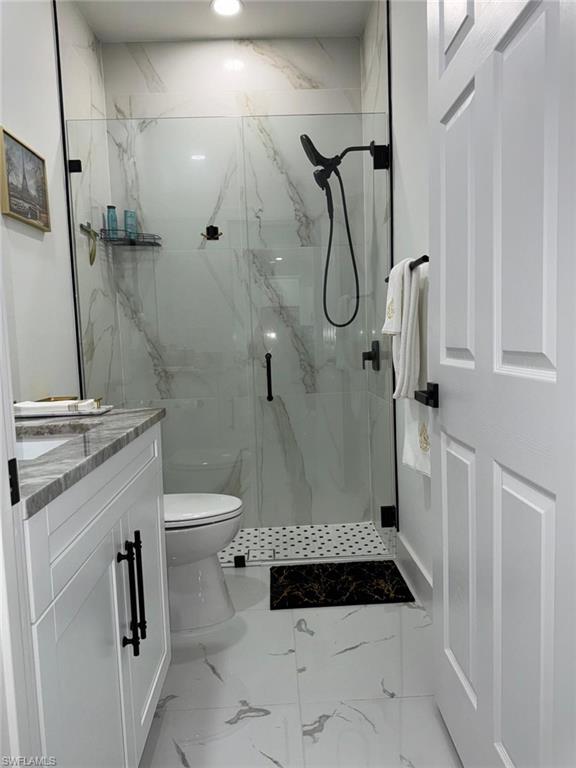 Full bathroom with vanity, toilet, marble finish floor, and a marble finish shower