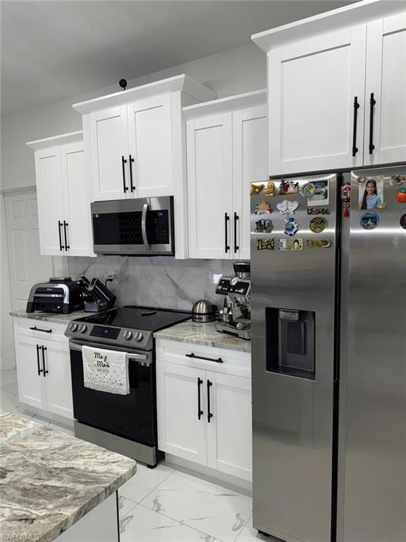 Kitchen featuring tasteful backsplash, marble finish floor, stainless steel appliances, and light stone counters