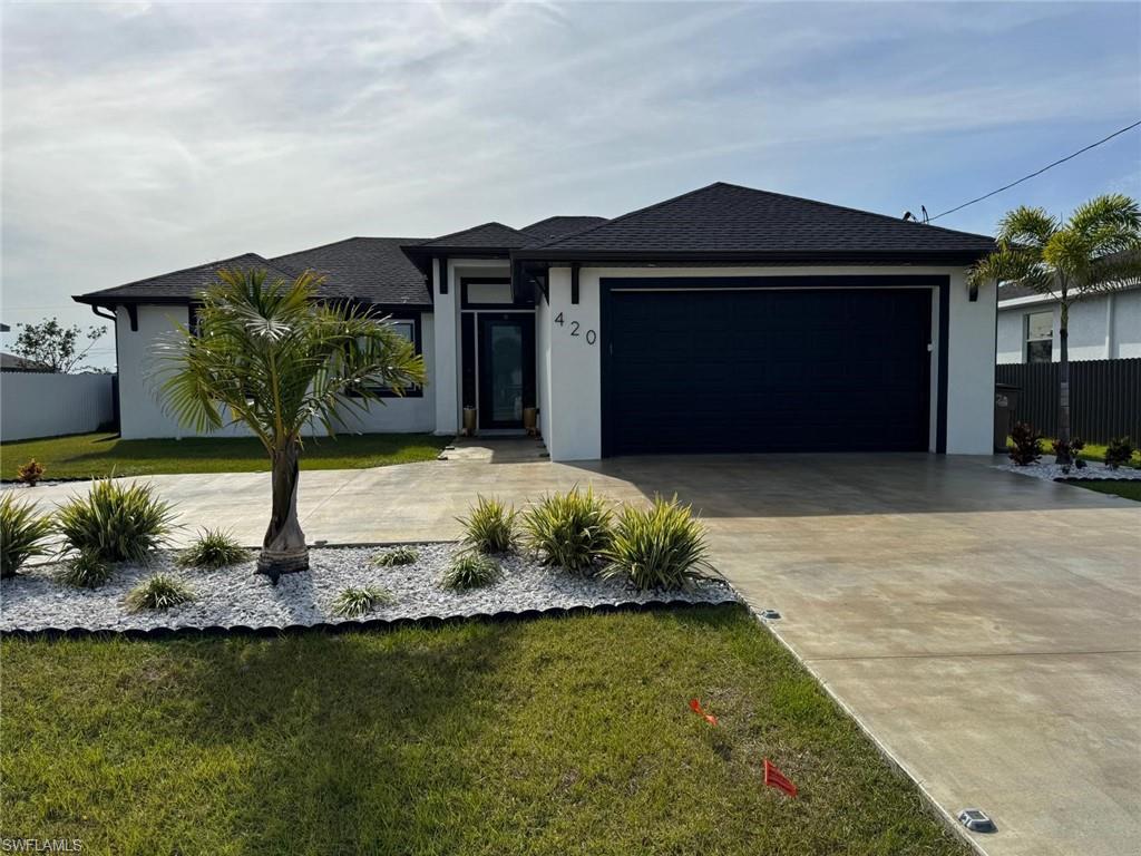 View of front of property with stucco siding, roof with shingles, concrete driveway, a front yard, and an attached garage