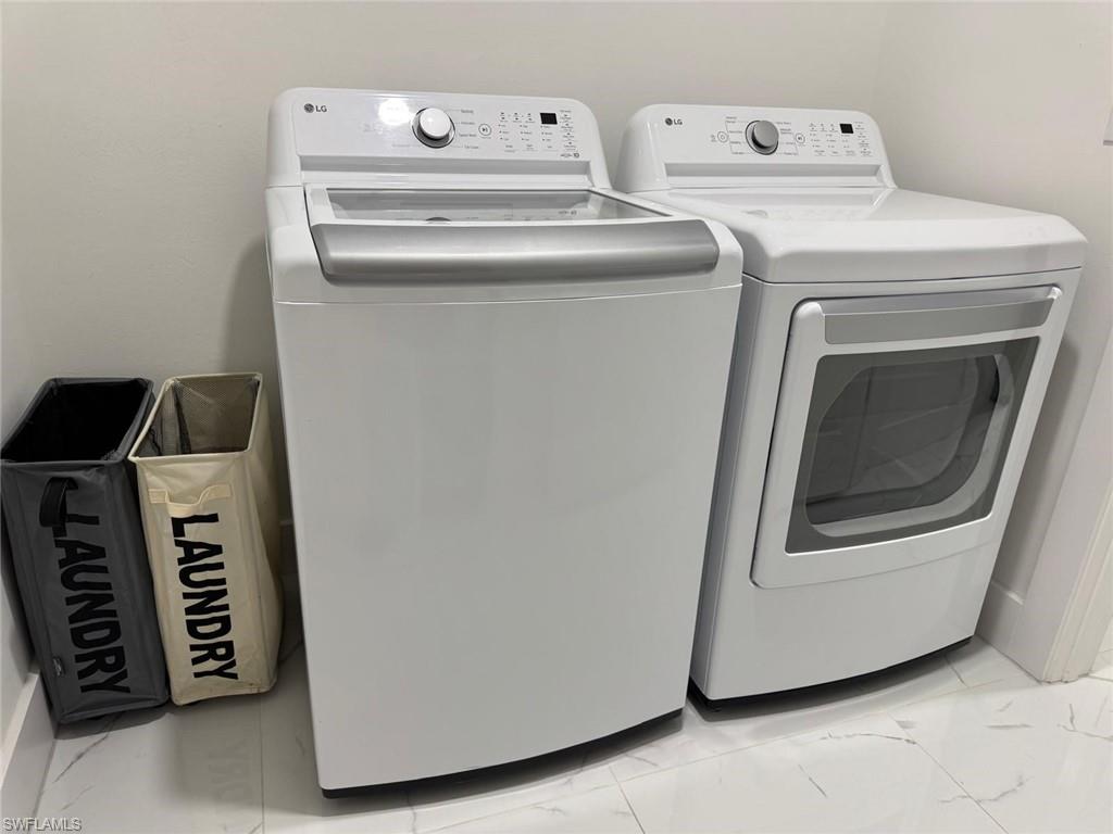 Laundry area with marble finish floor and washing machine and clothes dryer
