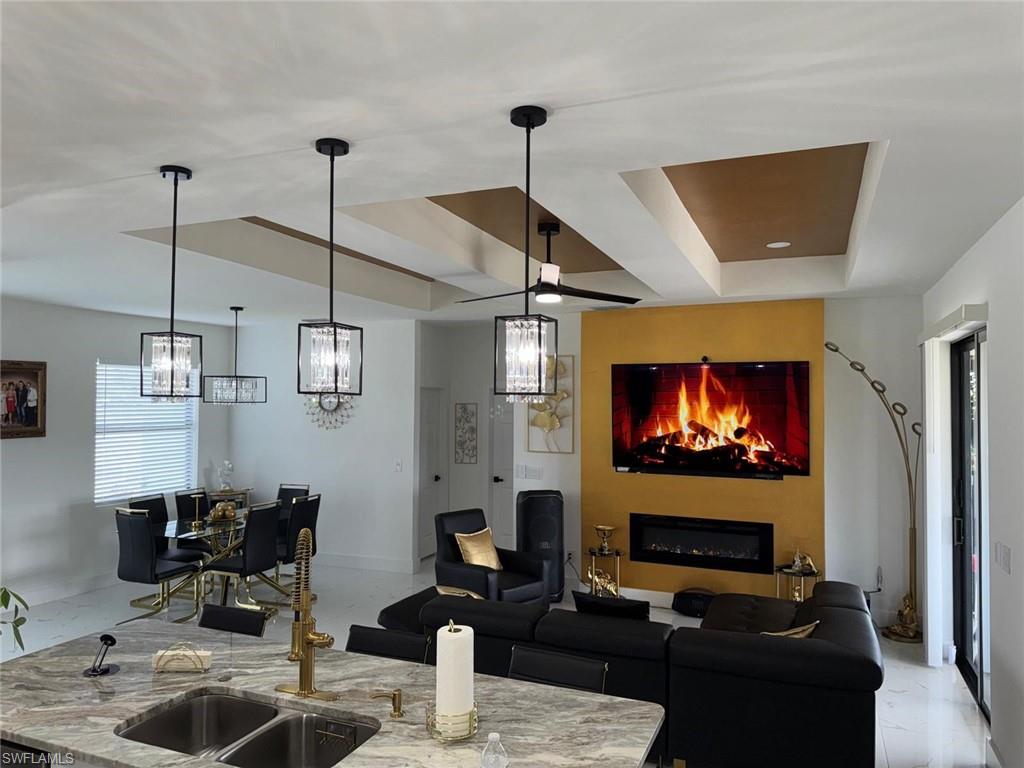 Living room featuring a raised ceiling, a fireplace, and a chandelier