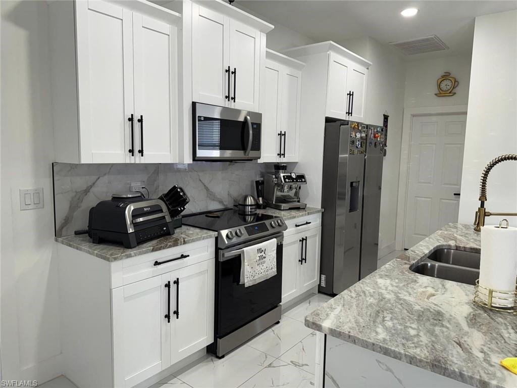 Kitchen featuring visible vents, a sink, white cabinets, appliances with stainless steel finishes, and marble finish floor
