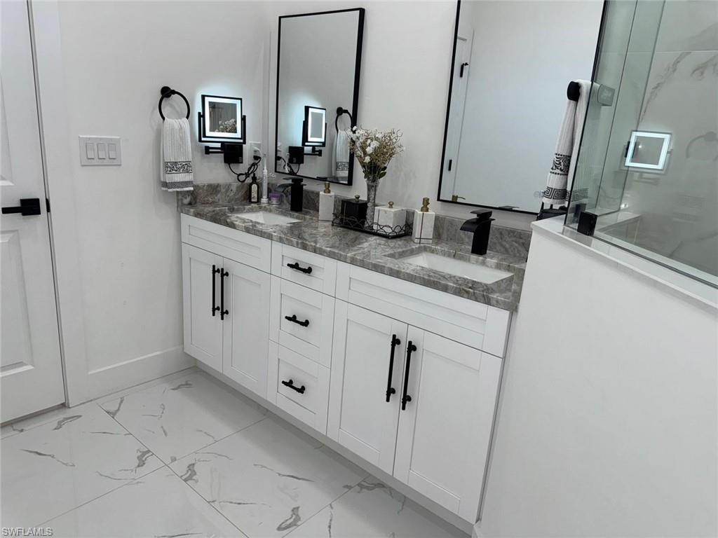 Bathroom with a sink, marble finish floor, double vanity, and a walk in shower