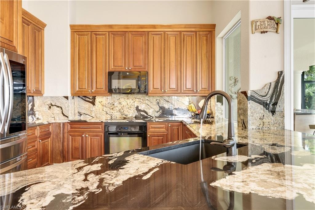 Kitchen featuring light stone countertops, wood finish cabinets, and black appliances
