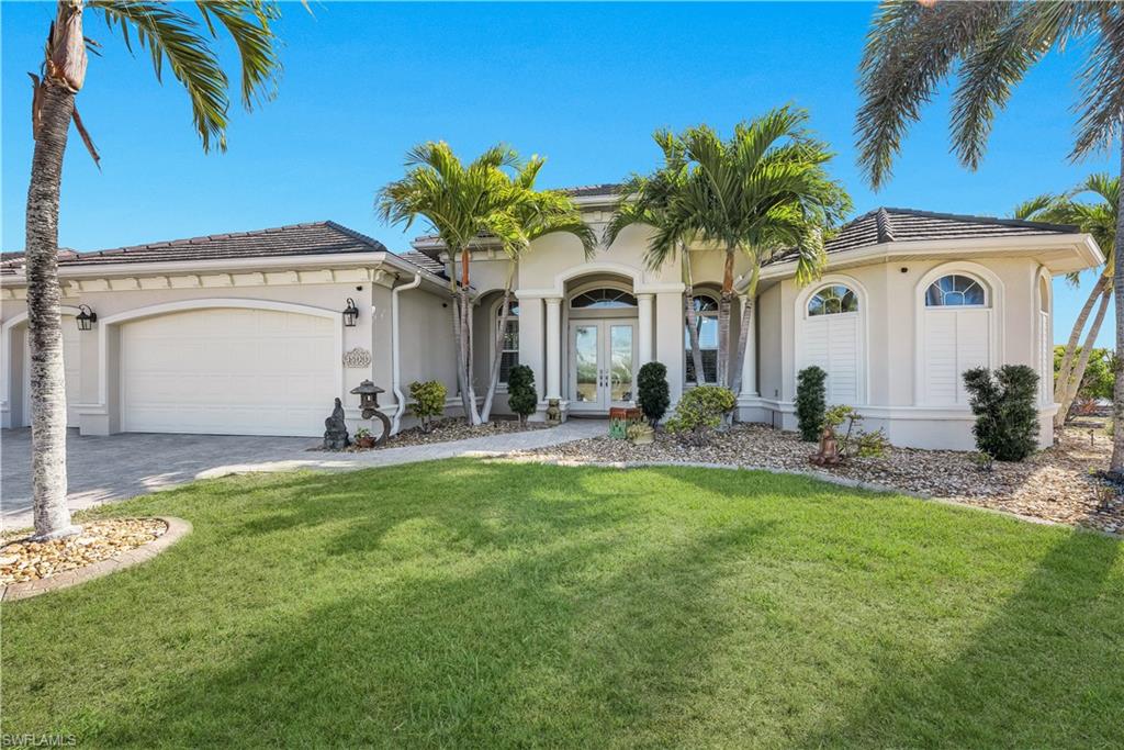 Mediterranean / spanish home featuring french doors, stucco siding, a front yard, and driveway