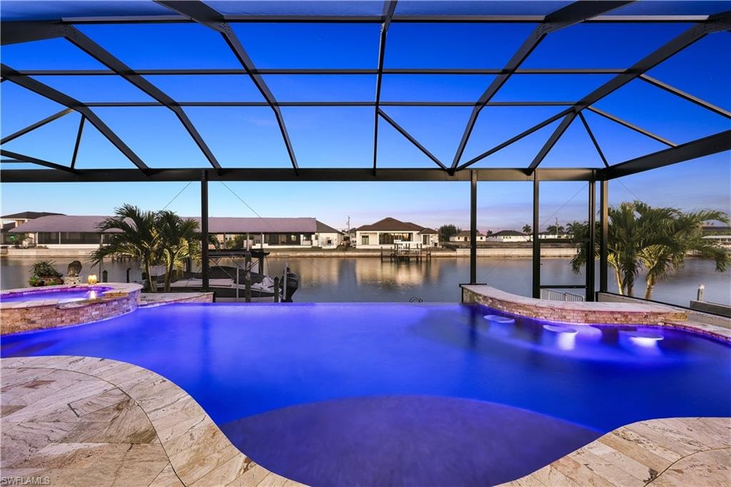 Integrated pool / spa with a lanai, a sunroom, and a water view