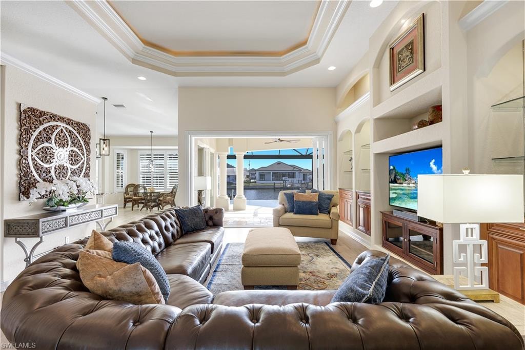 Living area featuring built in features, ornamental molding, recessed lighting, and a raised ceiling