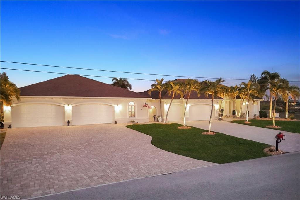 Ranch-style house featuring decorative driveway, a front yard, stucco siding, and an attached garage