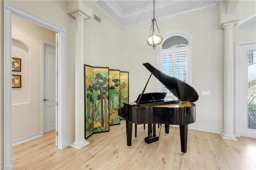 Living area with decorative columns, crown molding, and wood finished floors
