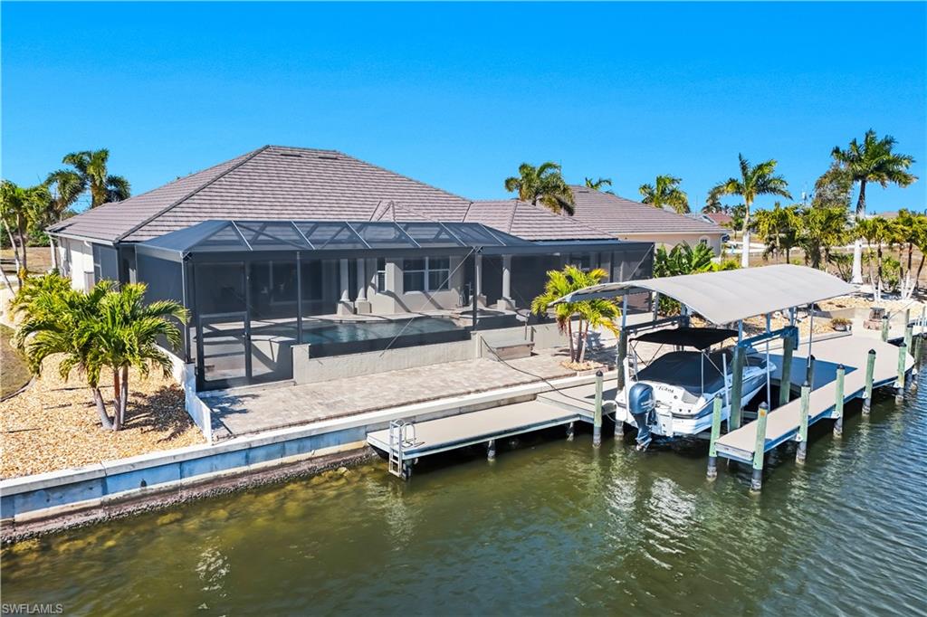 Rear view of house with an outdoor pool, a lanai, boat lift, a sunroom, and a water view