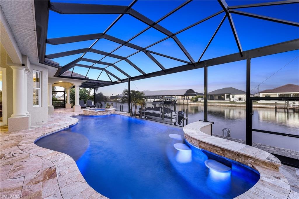 Combined pool / hot tub featuring a sunroom, glass enclosure, a water view, a patio, and a dock