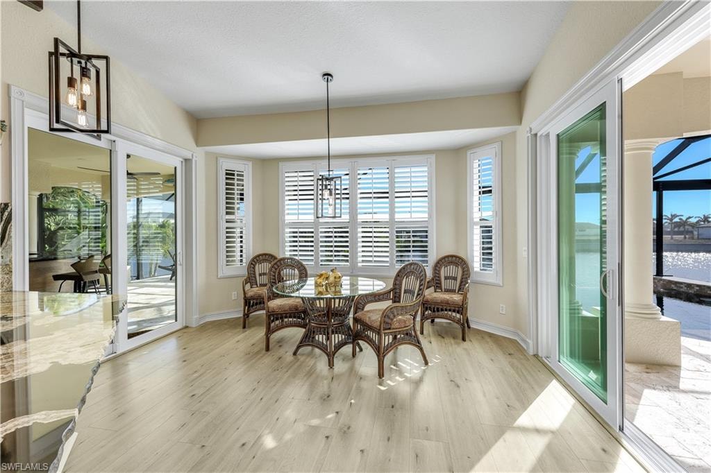 Dining space with suspended lighting, light wood-style flooring, and a water view
