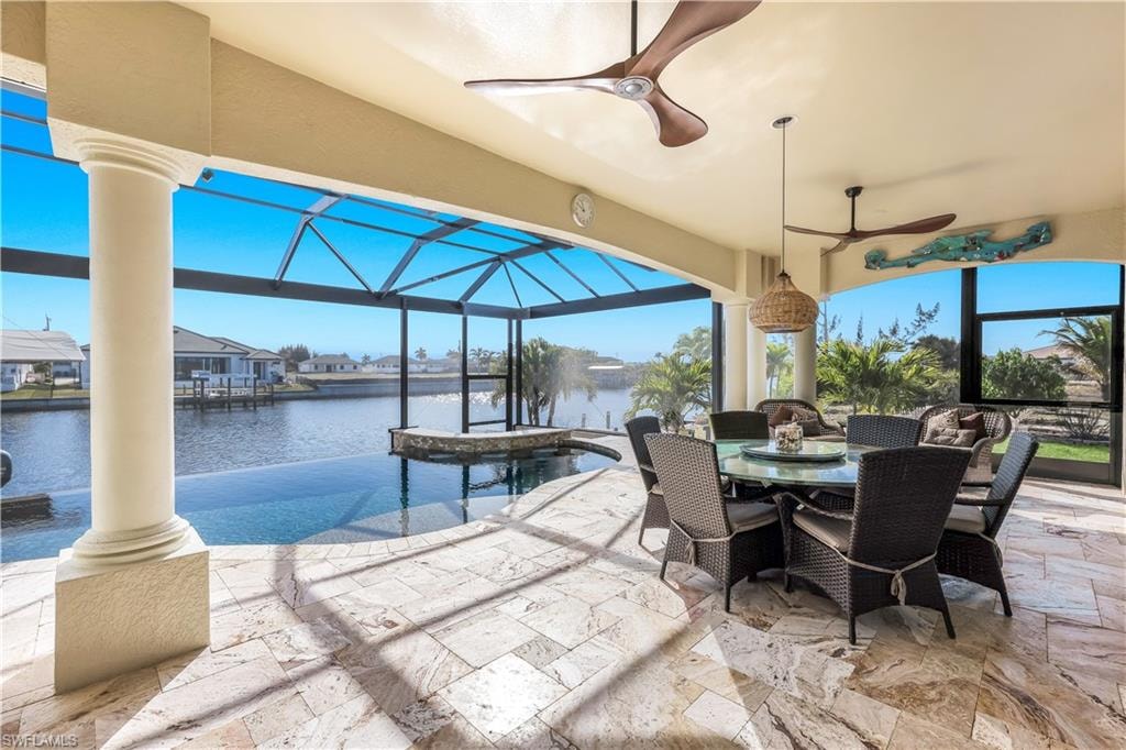 View of patio / terrace with a ceiling fan, a sunroom, outdoor dining space, glass enclosure, and a water view