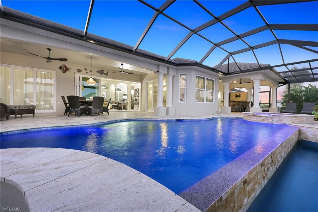Relaxing pool / spa with outdoor dining space, a patio, a sunroom, and glass enclosure