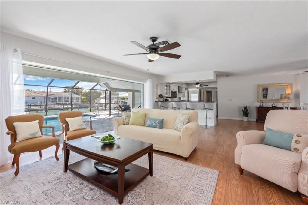 Living room featuring a sunroom, wood finished floors, and a ceiling fan