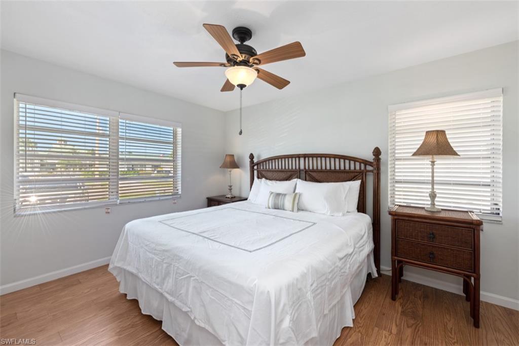 Bedroom featuring wood finished floors, multiple windows, and a ceiling fan