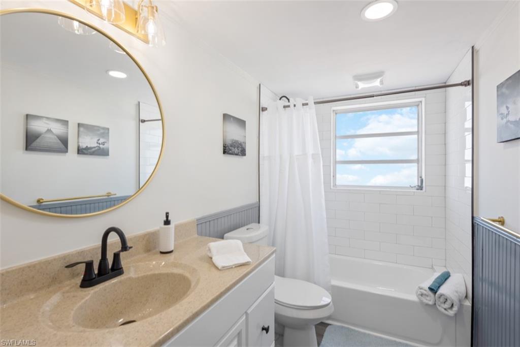 Full bath with vanity, shower / tub combo, wainscoting, recessed lighting, and ornamental molding