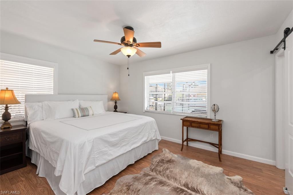 Bedroom featuring a barn door, wood finished floors, and a ceiling fan