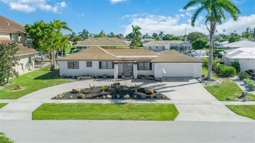 View of front of home featuring concrete driveway, an attached garage, a front lawn, a residential view, and roof with shingles