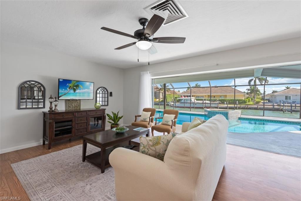 Living room with a sunroom, ceiling fan, and wood finished floors