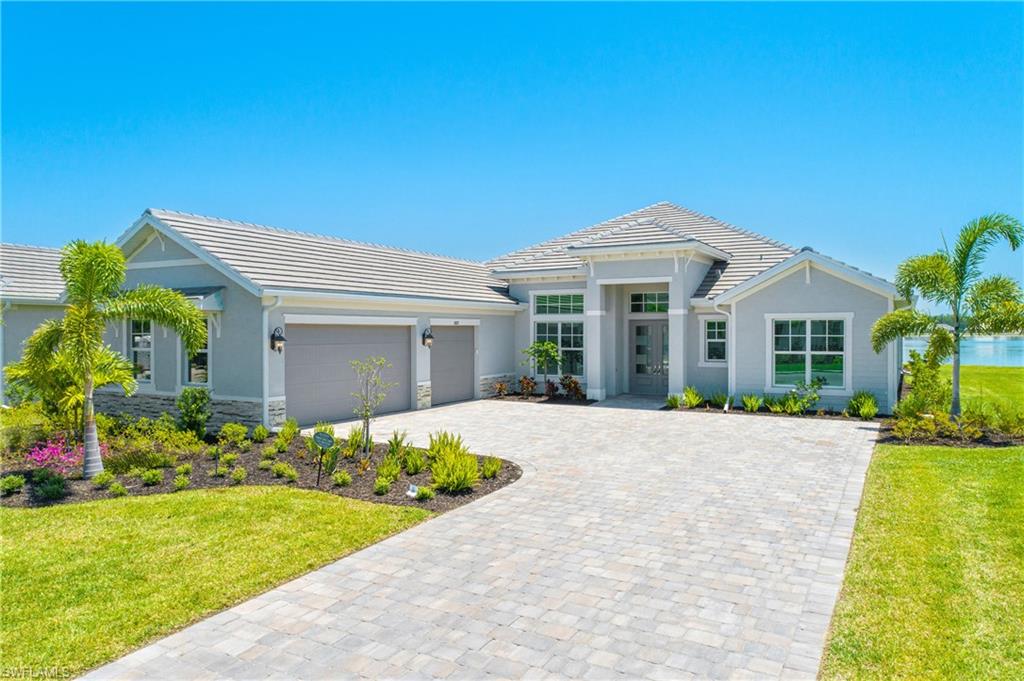 View of front of property with a front lawn, stone siding, stucco siding, decorative driveway, and a tile roof