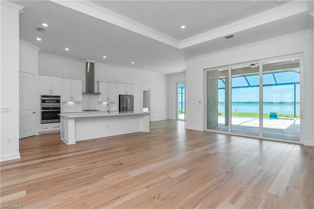 Kitchen featuring open floor plan, a center island with sink, white cabinetry, light wood finished floors, and recessed lighting