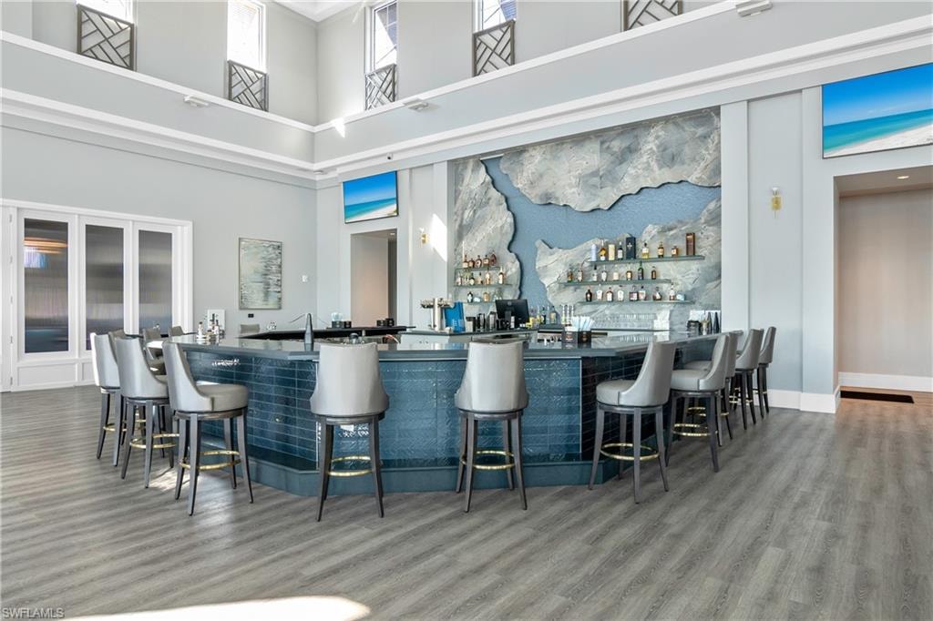 Community bar area featuring dark countertops, open shelves, and a high ceiling