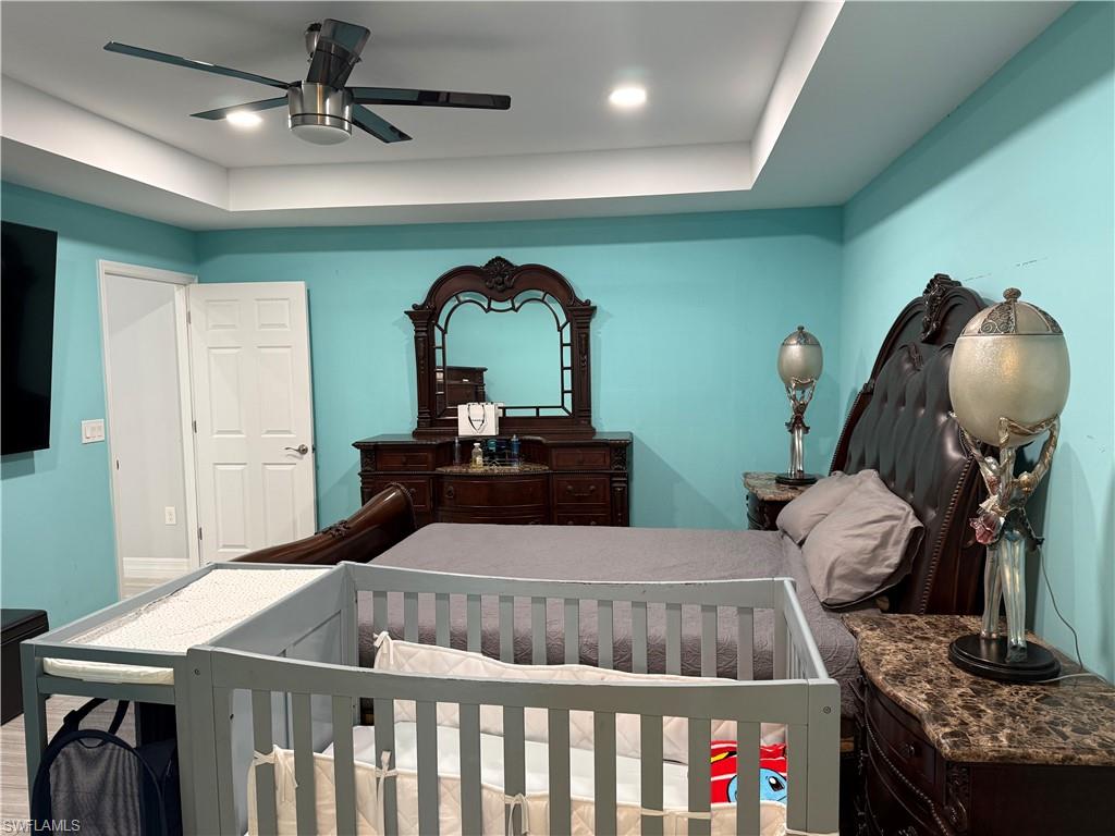 Bedroom featuring a tray ceiling, a ceiling fan, and recessed lighting