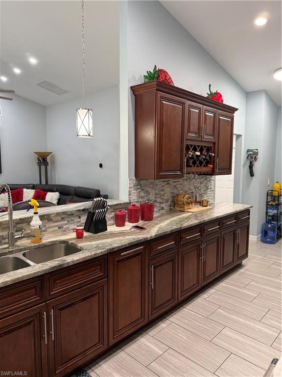 Kitchen featuring hanging light fixtures, light stone counters, lofted ceiling, wood tiled floors, and backsplash