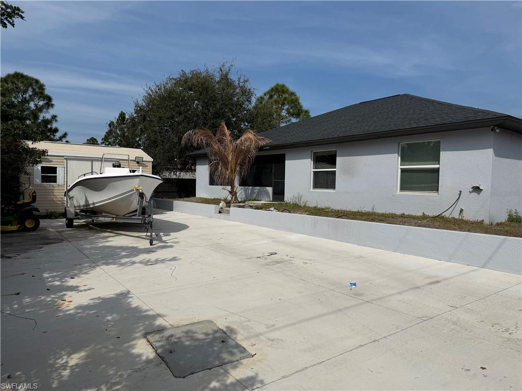 View of side of property with a shingled roof and stucco siding