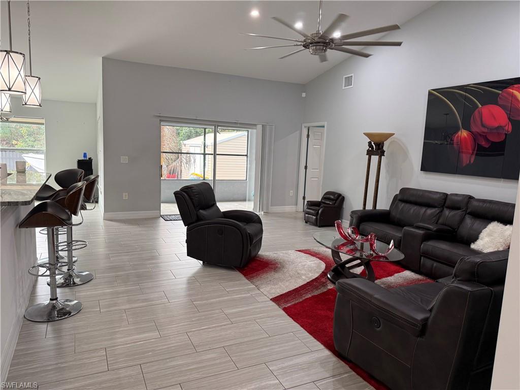 Living room featuring wood tiled floors, vaulted ceiling, and ceiling fan