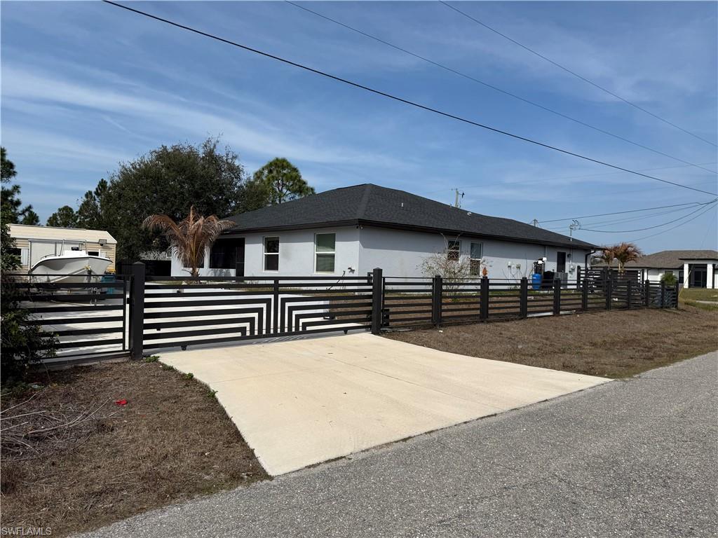 View of side of property featuring a fenced front yard, a gate, and stucco siding