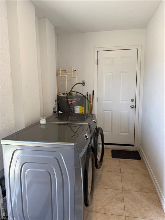 Laundry area with washer and dryer, light tile patterned flooring, and water heater