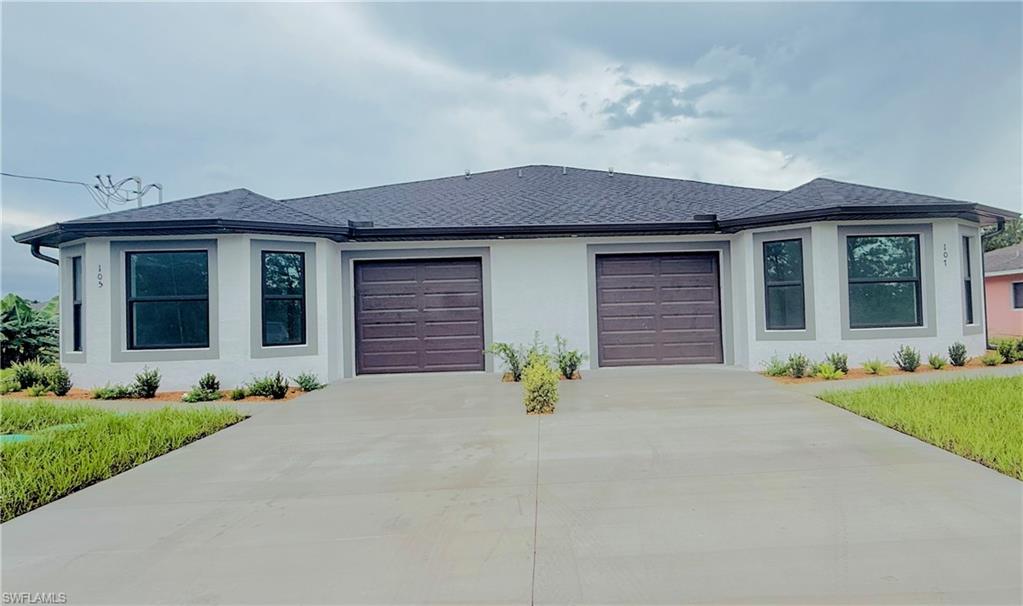View of front of home featuring a shingled roof, a garage, driveway, and stucco siding
